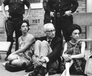 A.J. Muste and two other protesters sit with police standing behind them
